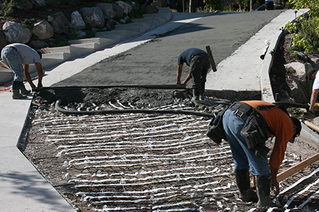 Pouring concrete over heat cable during heated driveway installation.